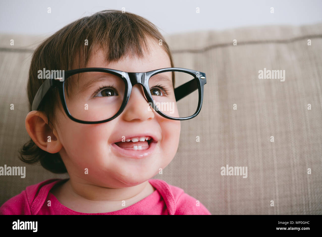 Portrait of laughing baby girl wearing oversized glasses Stock Photo
