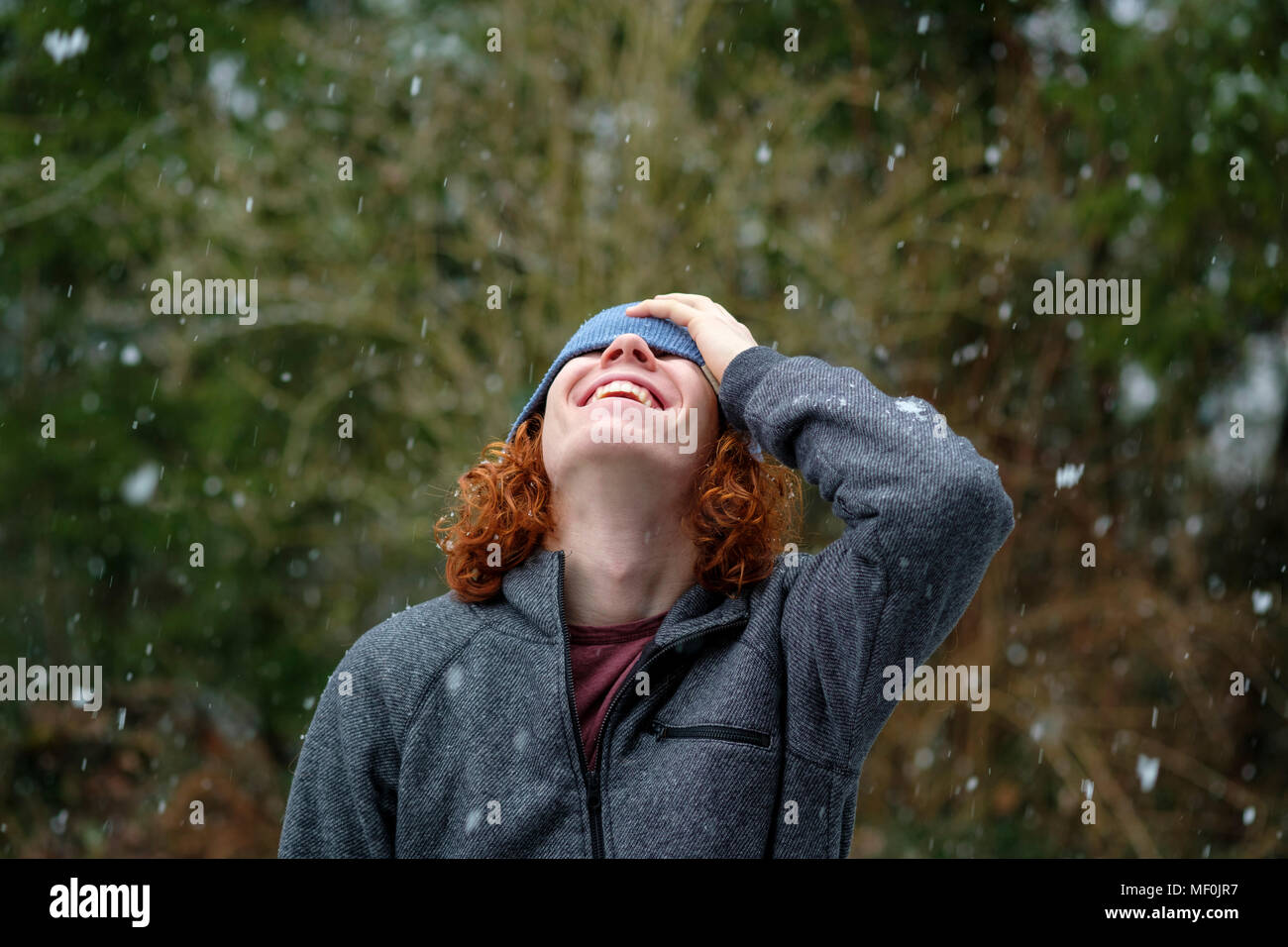 junger Mann mit Mütze lacht und freut sich über den Schnee, Oberbayern, Bayern, Deutschland Stock Photo