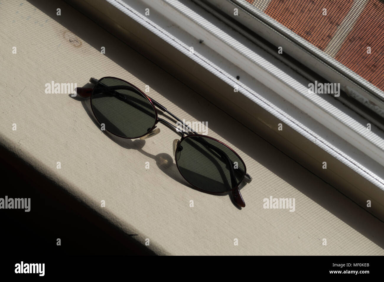 Sunglasses sitting a window sill. Stock Photo