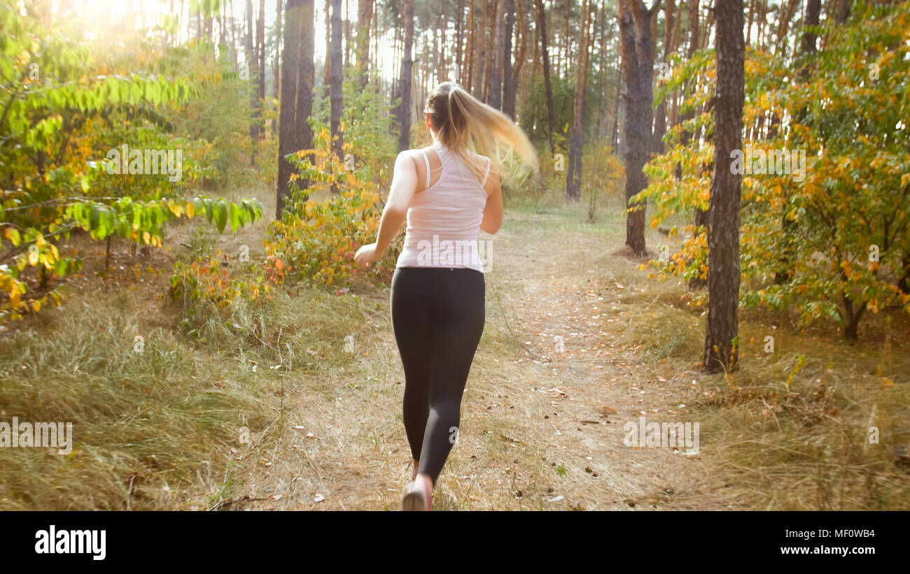 Rear view photo of young woman running on pathway at forest Stock Photo
