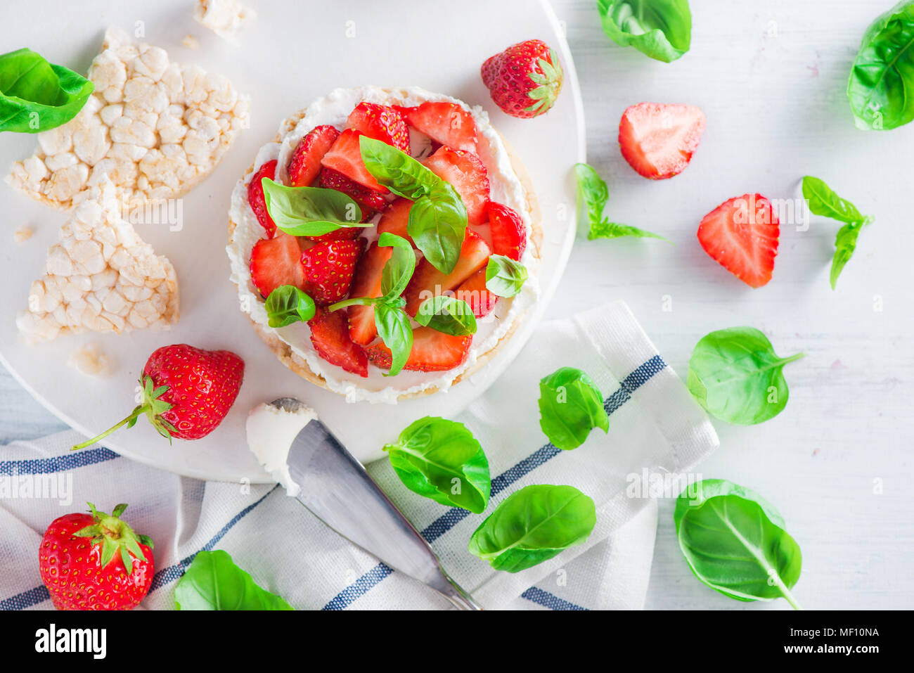 Healthy snack with crisp bread, fresh strawberries, goat cheese, and basil leaves. Easy appetizer recipe. Stock Photo