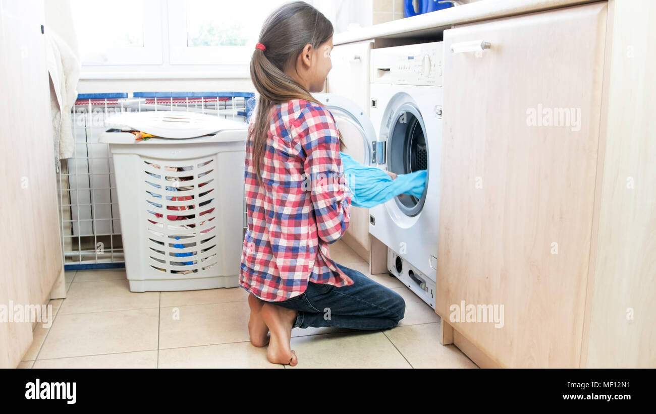 Teenage girl taking wet clean clothes out of washing maching at laundry room Stock Photo Alamy