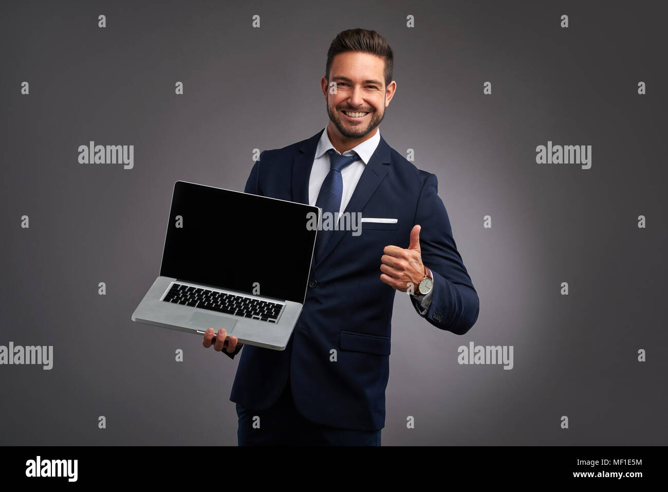 An elegant handsome young man holding and showing the screen of a ...