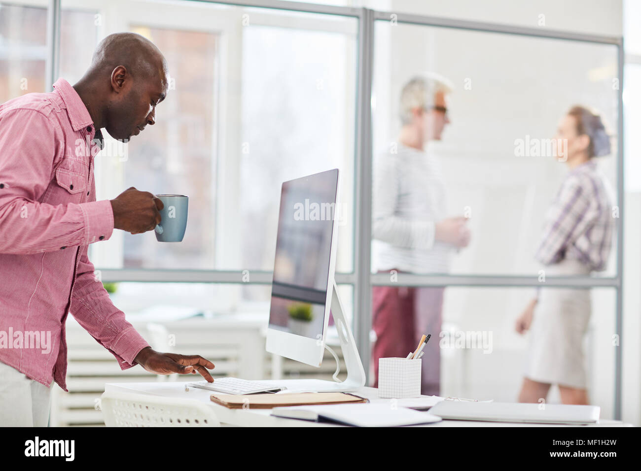 African casual businessman typing on computer while drinking coffee Stock Photo