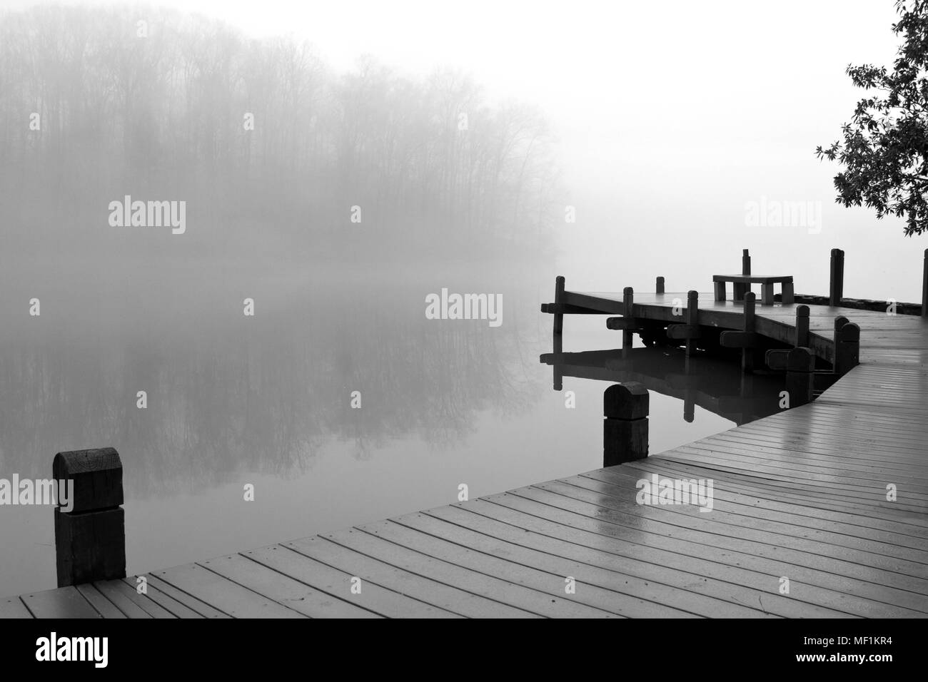 Fog covers a lake and wooden deck on a dreary winter day. Stock Photo