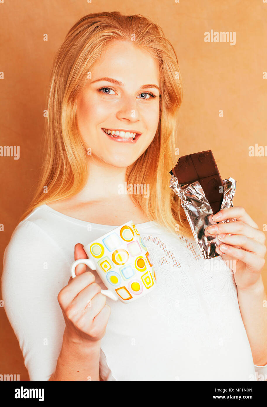 young cute blond girl eating chocolate and drinking coffee close Stock