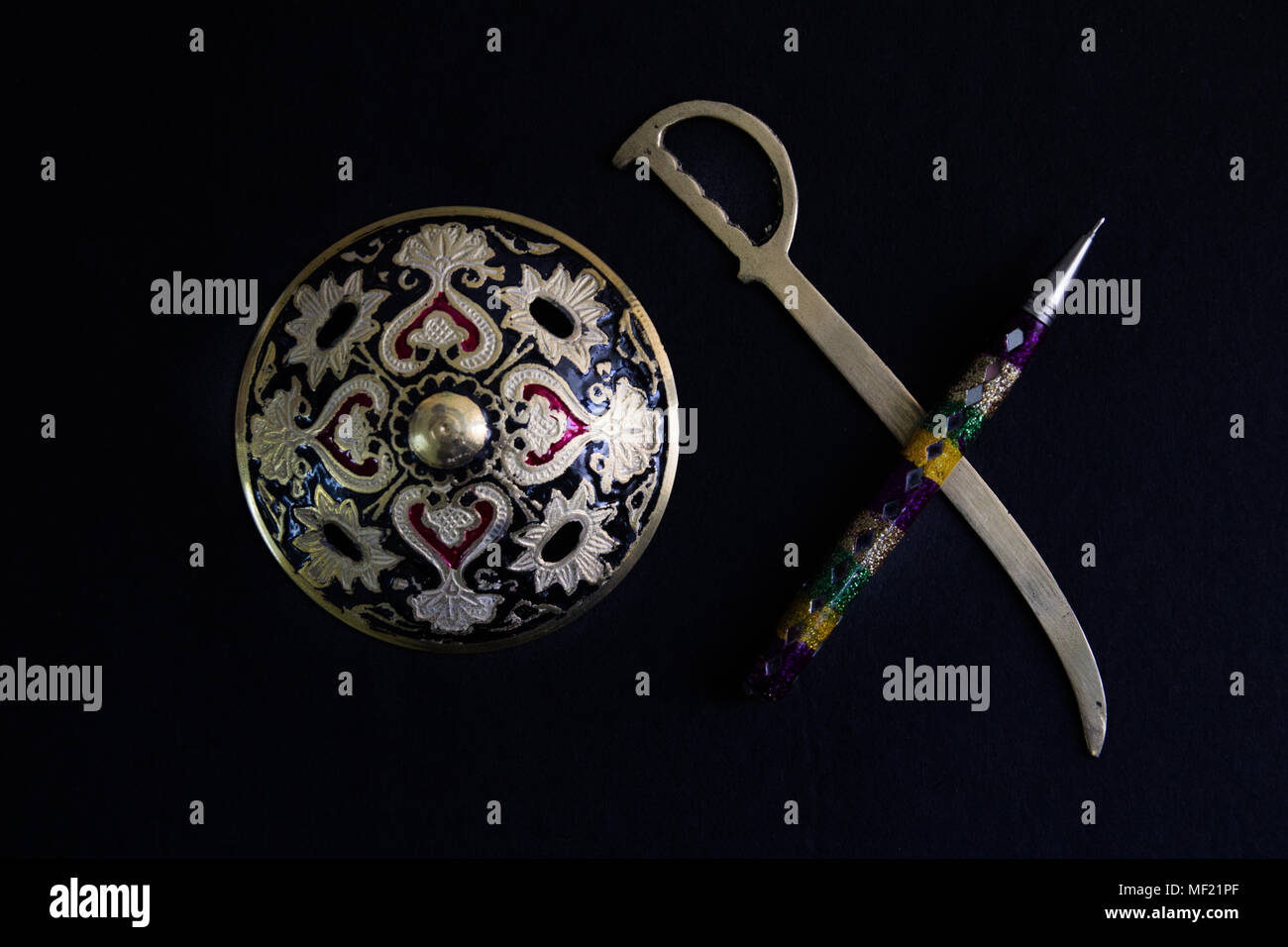 pen is mightier than sword concept by decorated round sword shield and pen in black background .antique artefact Stock Photo