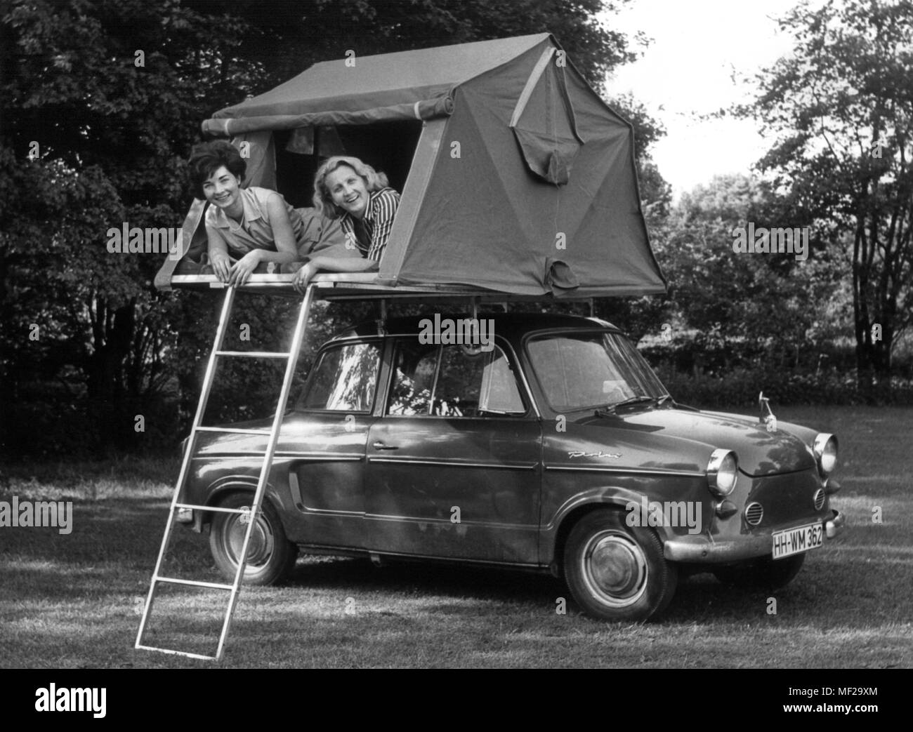 Two young women lie in a camping car roof tent mounted on a NSU prince. The camping tent on the car roof was presented on 16.06.1966 in Hamburg as a trade fair novelty from Milan. It is two meters long and 1.30 meters wide and is intended as a sleeping place for two people and one child. Fitting for any car, it attaches as a low package on the car roof, like a simple luggage rack. Photo: Georg Spring     (c) dpa - report     | usage worldwide Stock Photo