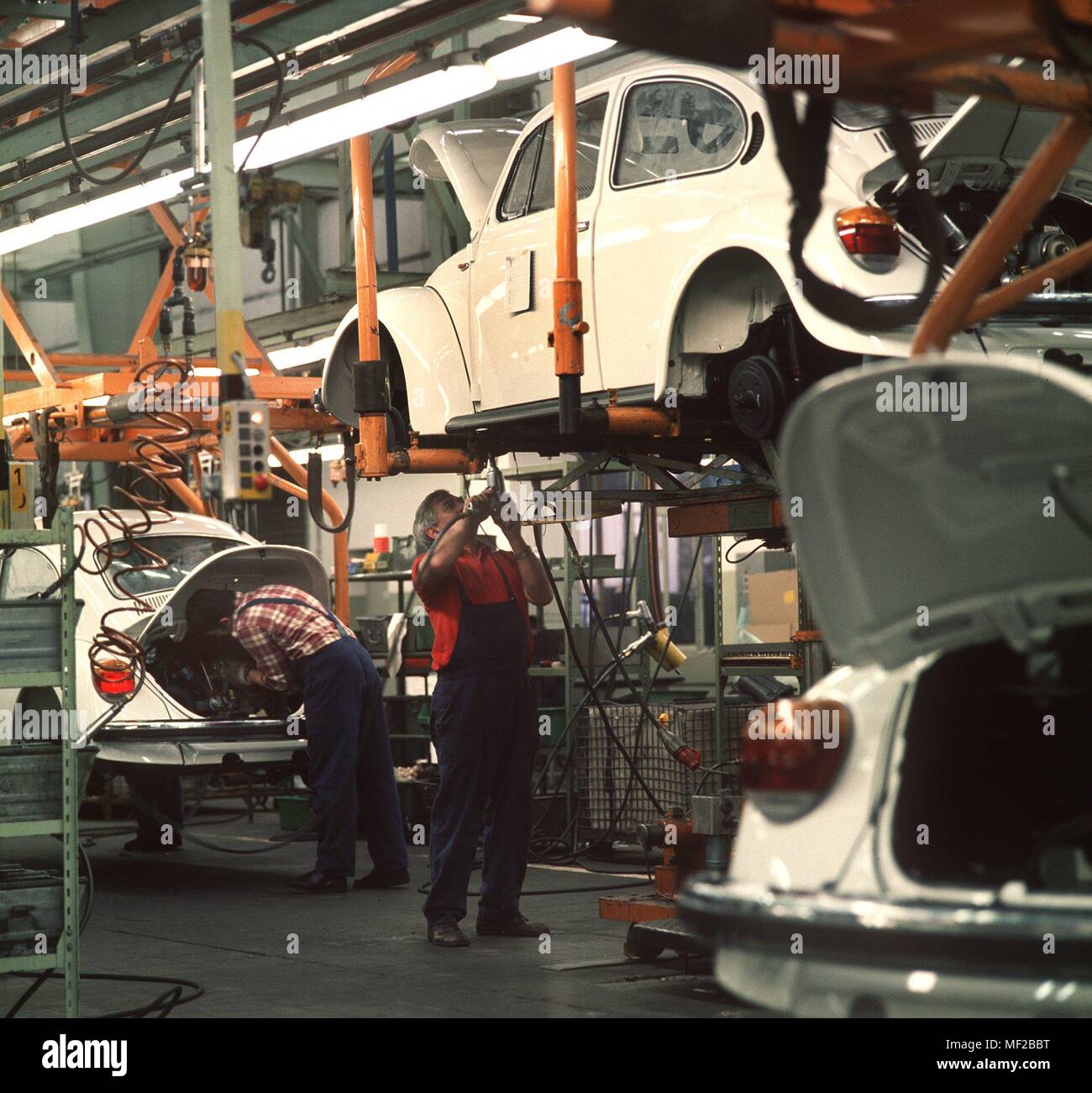 Worker mounting on engine and underbody panel of VW Kafern in VW plant in Emden. It is the last production of German VW Kafern. At the time of taking pictures, only 44 cars ran daily across the line. The workers were no longer fully utilized and further production was transferred to the VW plant in Mexico. Recorded 1978. | usage worldwide Stock Photo