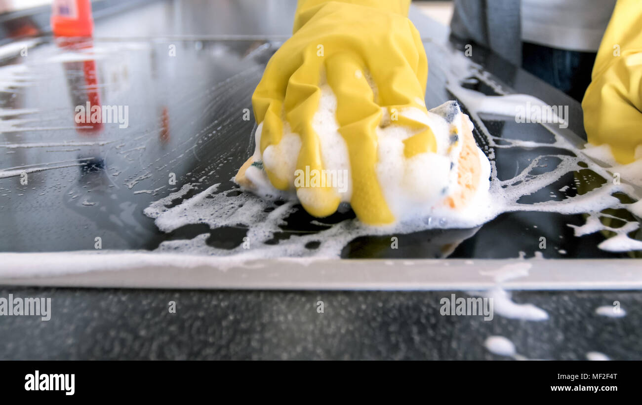Closeup image of hand in yellow rubber glove holding sponge with suds ...