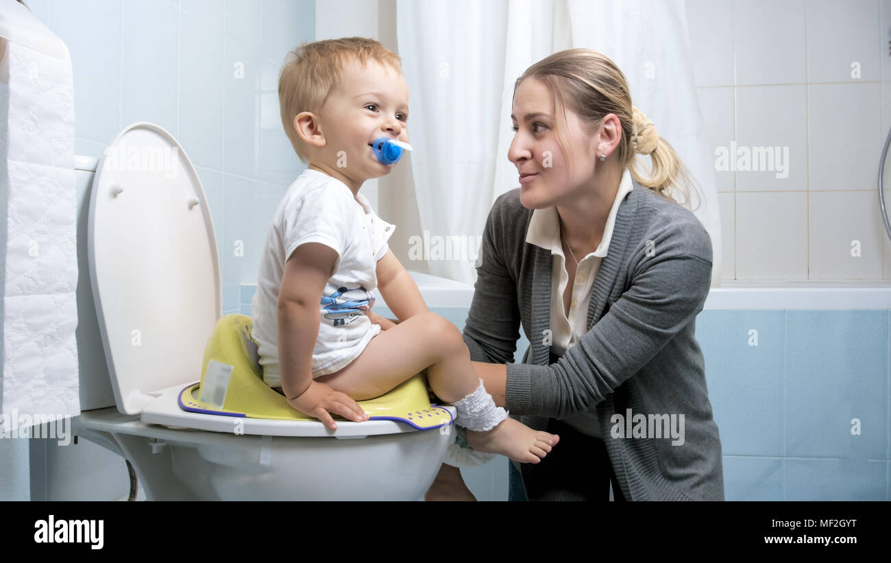 Young mother explaining to her toddler son how to use toilet Stock Photo -  Alamy