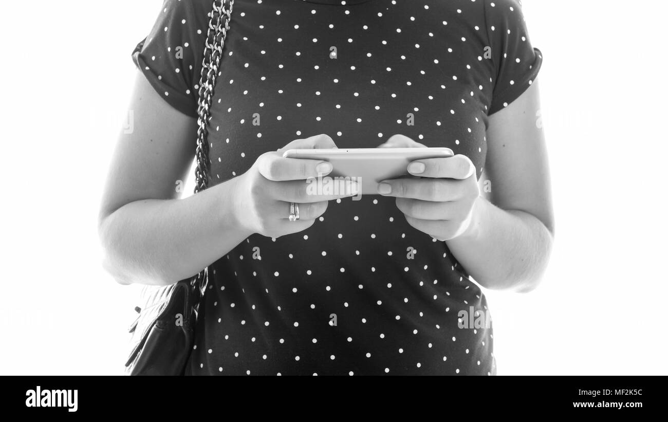 Black and white closeup photo of young woman with handbag holding mobile phone Stock Photo