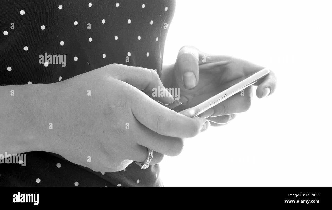 Black and white closeup image of young woman with smartphone in hands Stock Photo