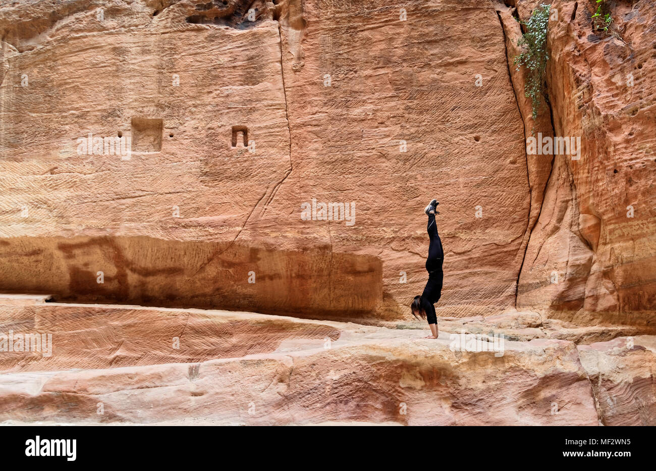 Petra, Wadi Musa, Jordan, March 9, 2018: Young European girl training a handstand in the Siq of Petra, middle east Stock Photo