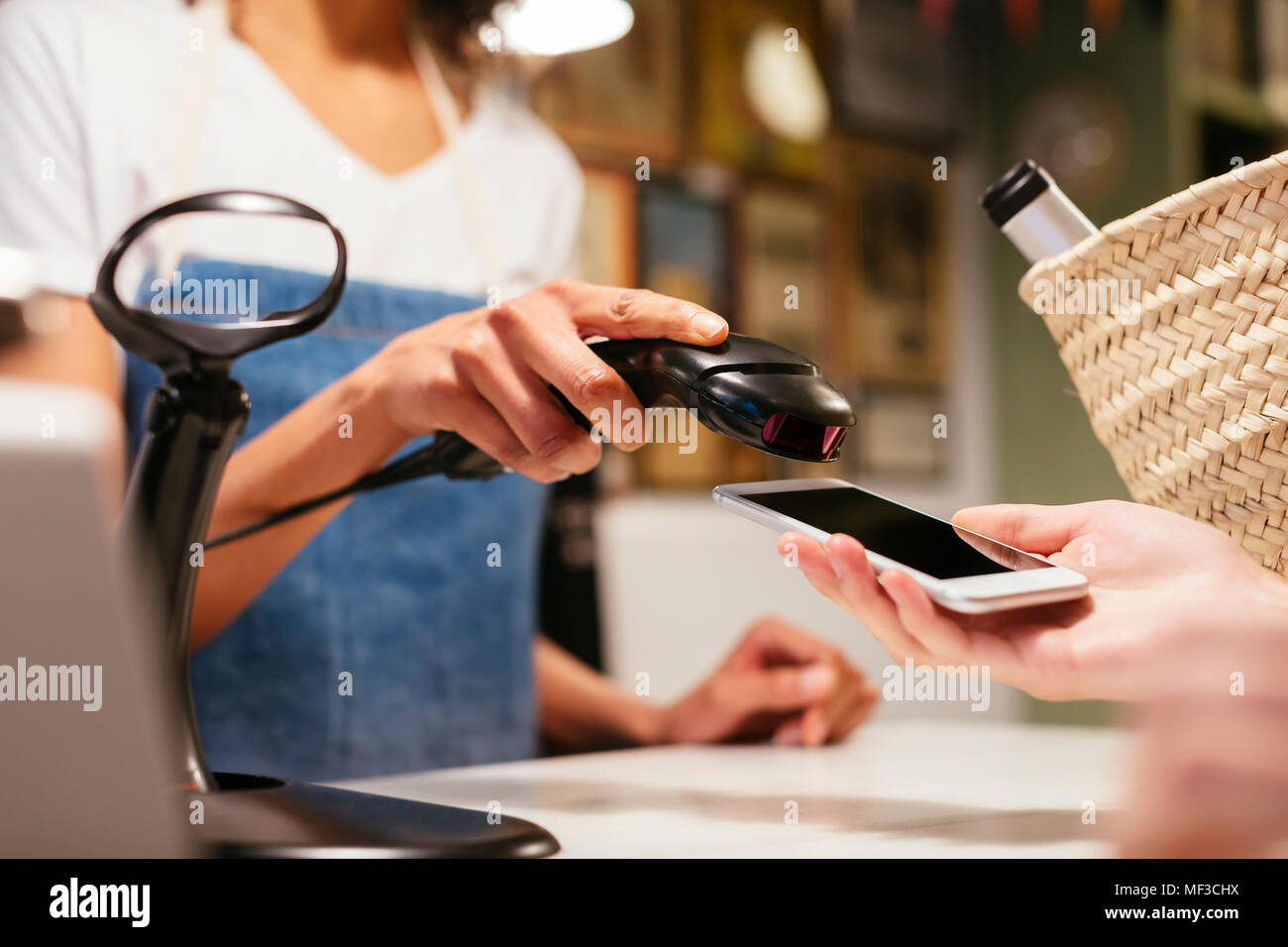 Close-up of customer paying cashless with smartphone at counter of a store Stock Photo