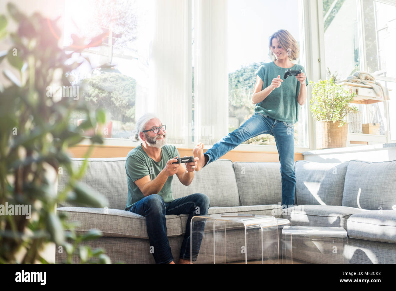 Happy mature couple on couch at home playing video game Stock Photo