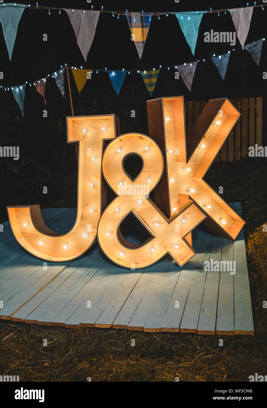 Handmade wooden letters illuminated with light bulbs on a night field party Stock Photo