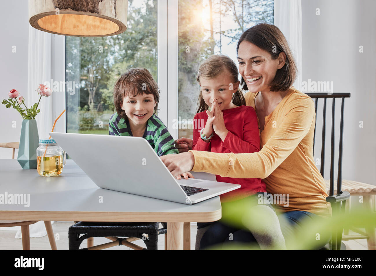 Happy mother with two children using laptop at home Stock Photo