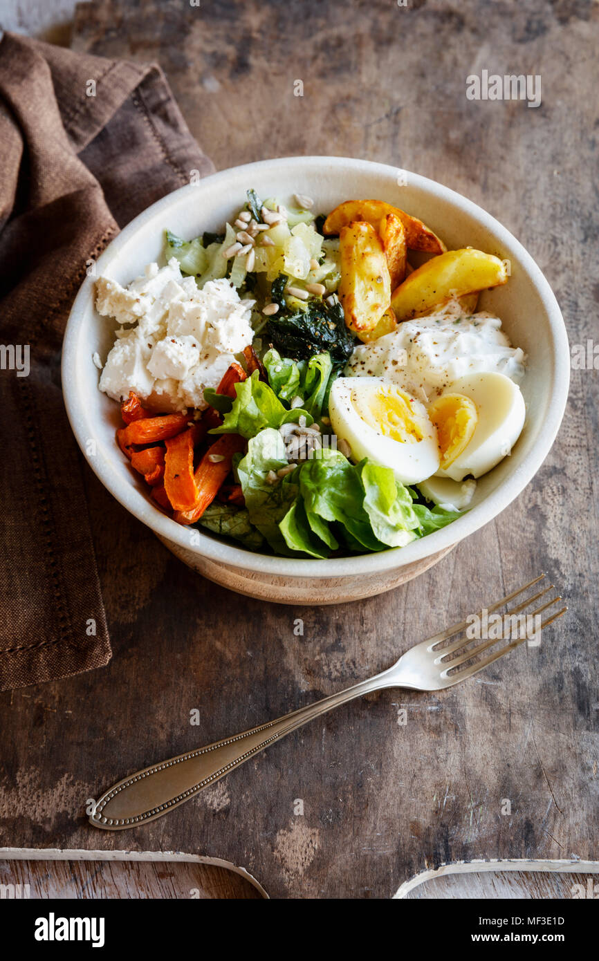 Lunch Bowl with baked potato and carrot, herbed curd cheese, salad, mangold, feta and boiled egg Stock Photo