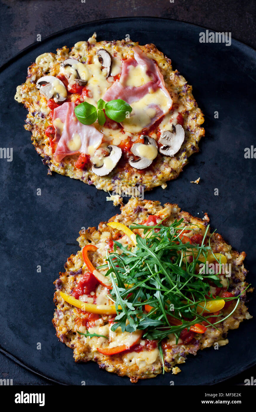 Cauliflower pizza garnished with rocket and bell pepper and champignons and cooked ham Stock Photo