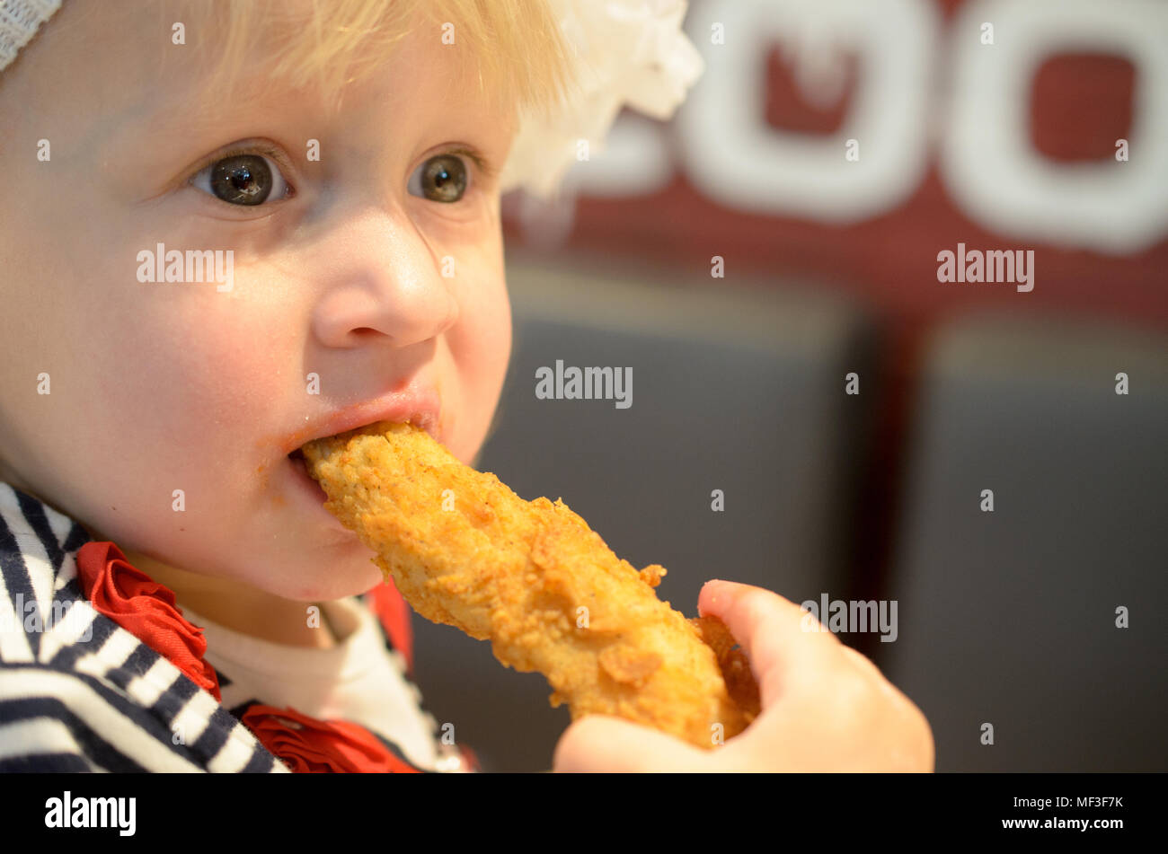 Portrait of one year old and eight month child, Baby girl eating a chicken wing Stock Photo