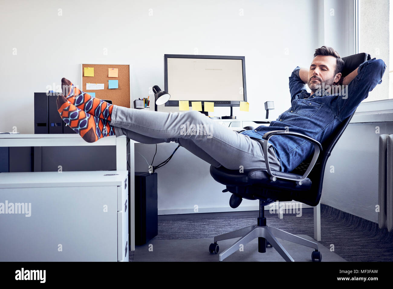 Man sitting at desk in office having a power nap Stock Photo