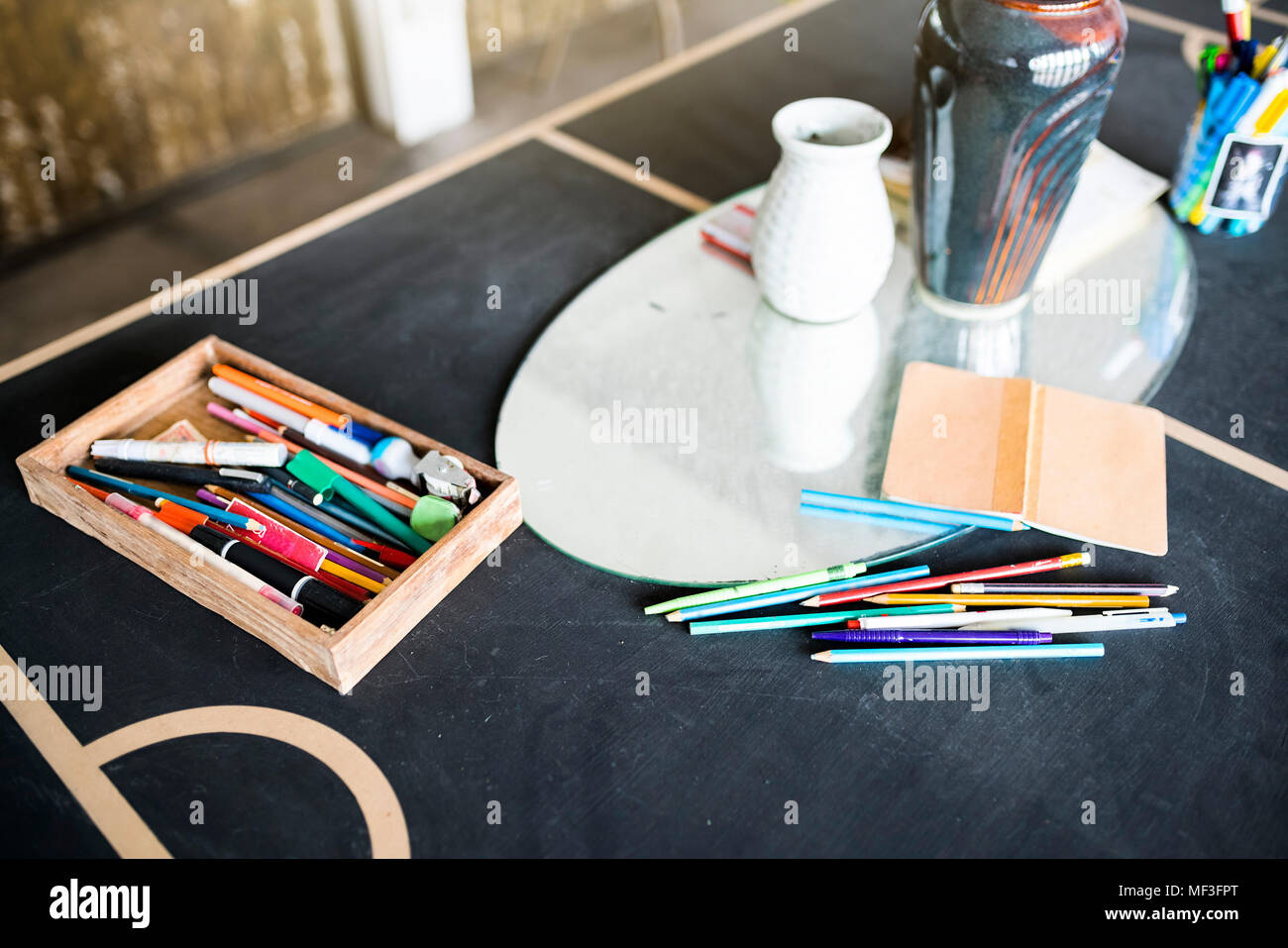 Crayons, pens and a notebook on a table in artist's studio Stock Photo