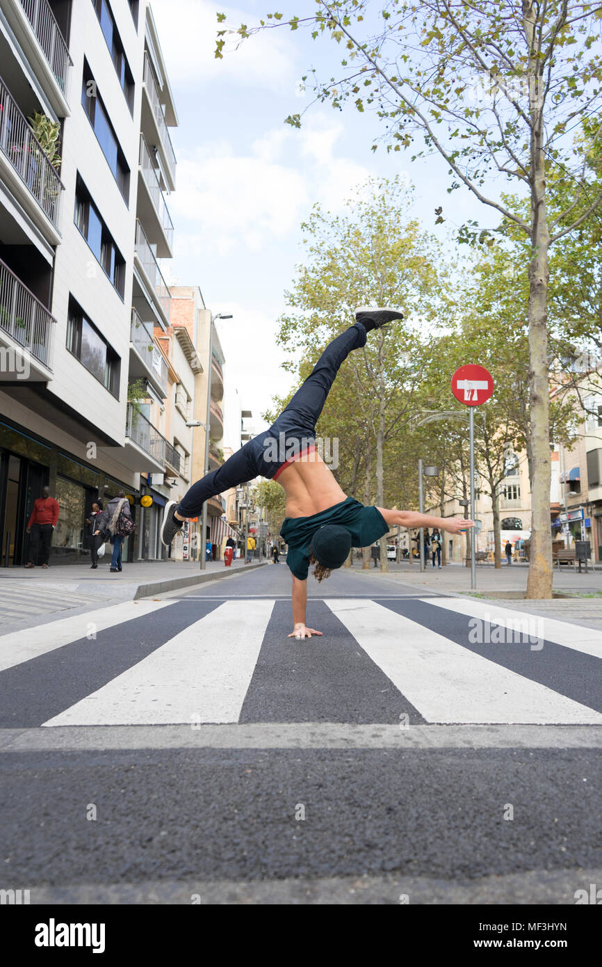 Back view of young man doing handstand on zebra crossing Stock Photo