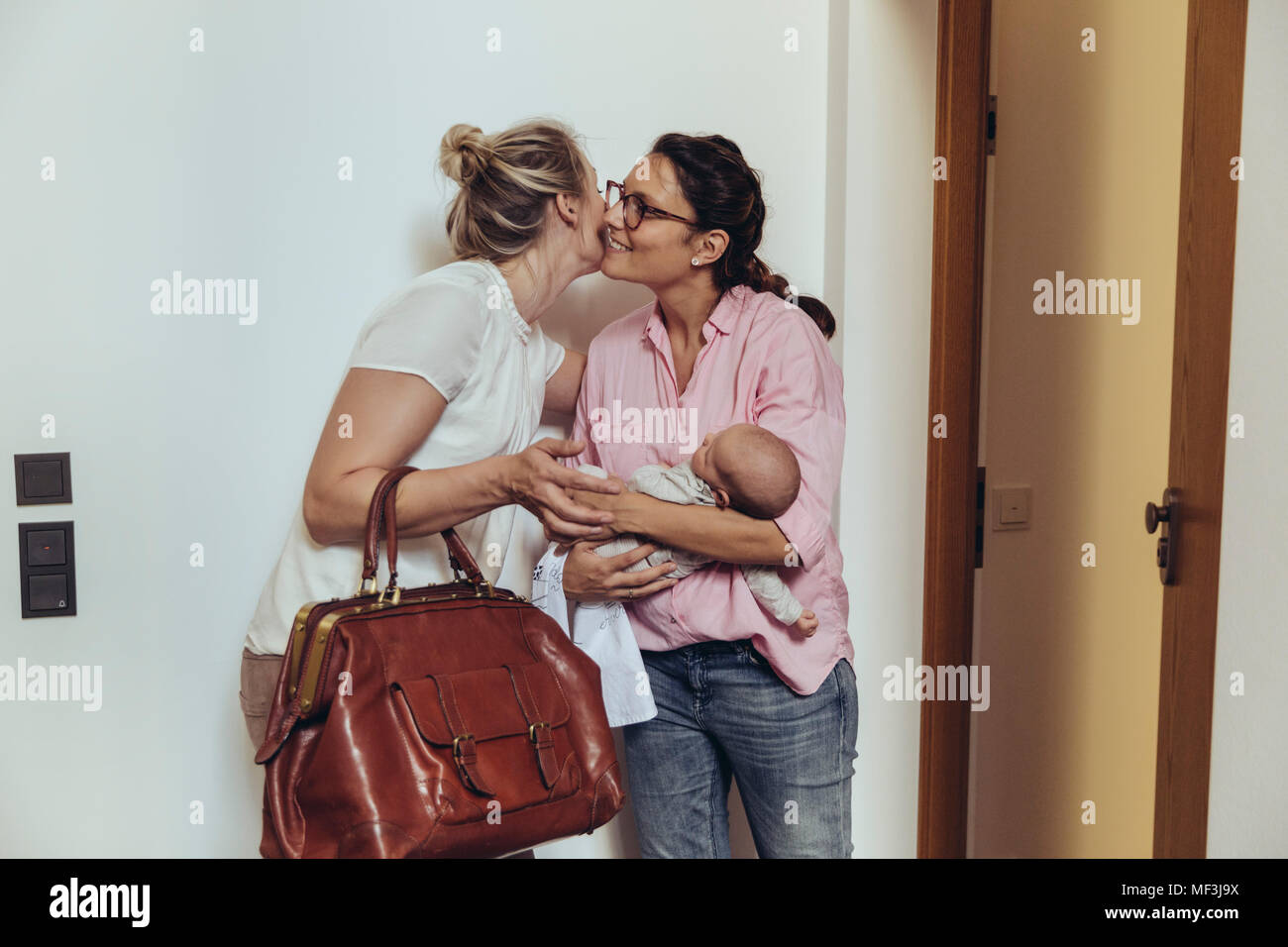 Woman greeting midwife at her home‚Äôs apartment door Stock Photo