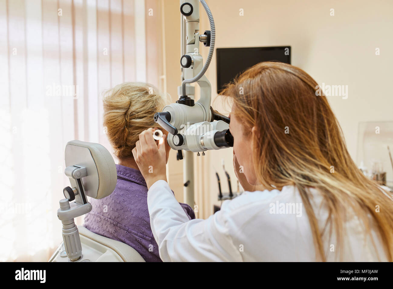 ENT physician examining ear of a senior woman Stock Photo