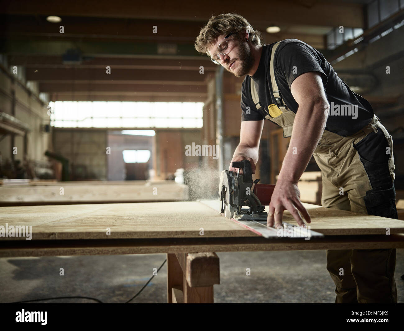 Carpenter sawing wood with handsaw Stock Photo