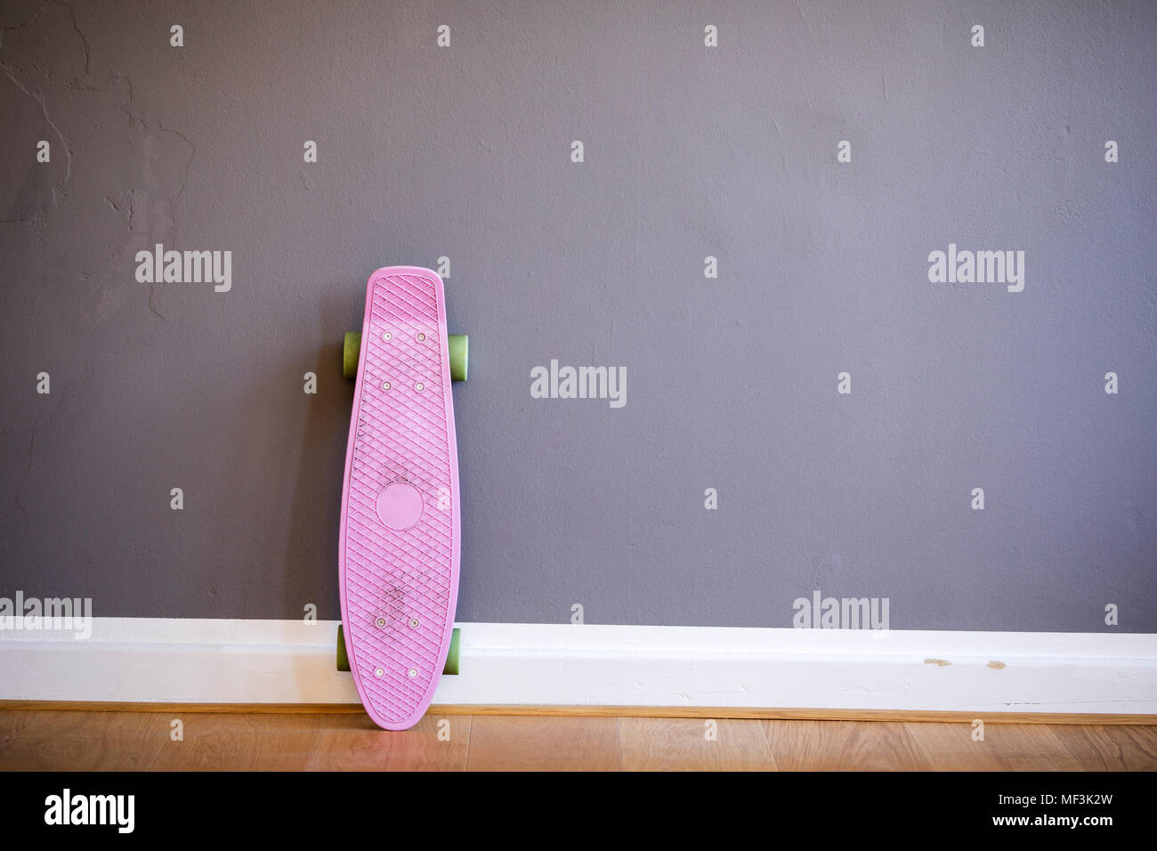 Pink skateboard leaning against wall Stock Photo