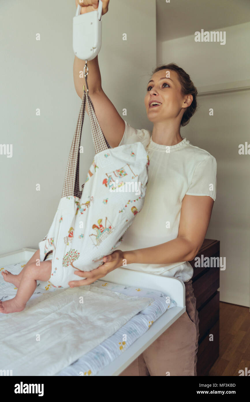 Midwife using baby scales to weigh newborn Stock Photo