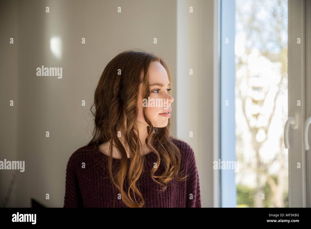 Teenage girl looking out of window, daydreaming Stock Photo