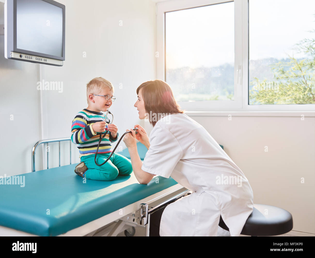 Female doctor and boy with stethoscope in medical practice Stock Photo