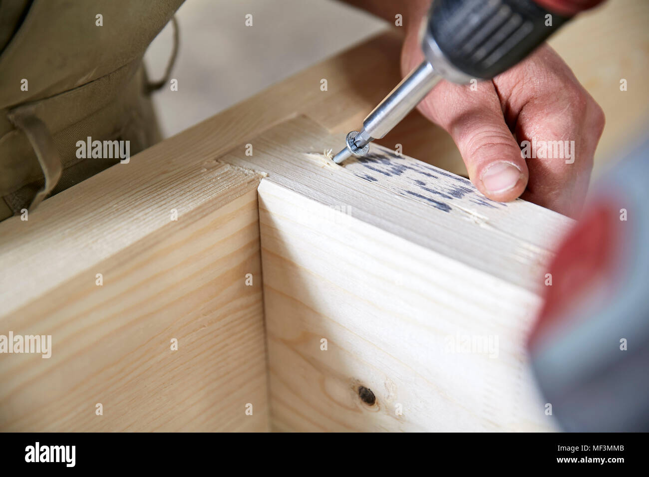 Carpenter fixing wooden construction with portable drill Stock Photo