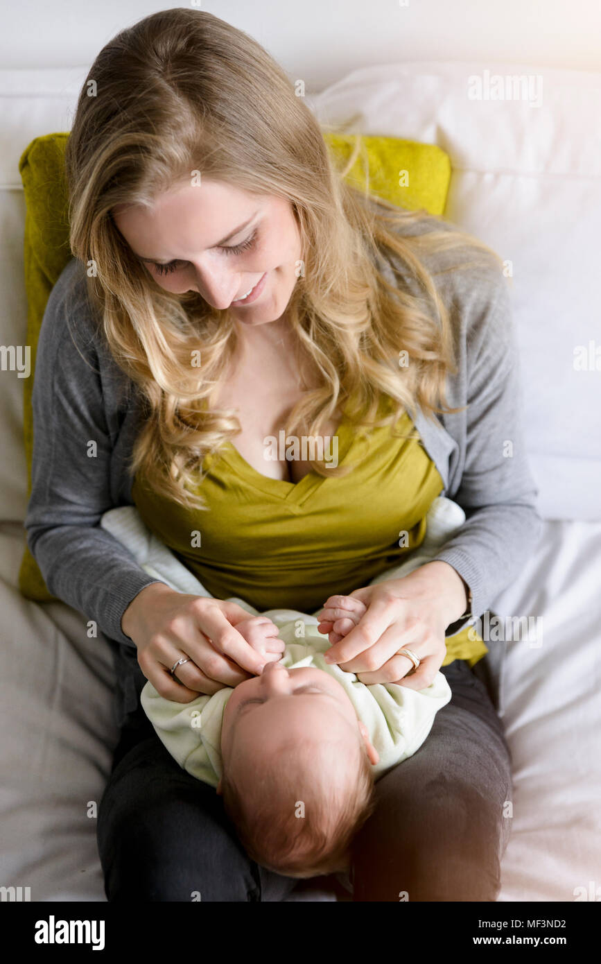 Smiling mother with her baby boy, lying on lap Stock Photo