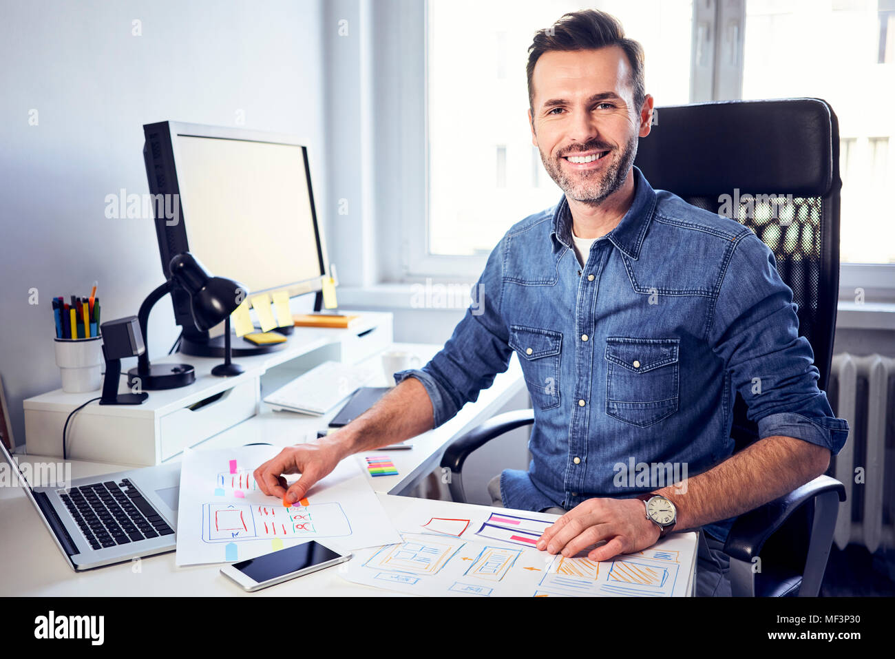 Portrait of smiling web designer working on draft at desk in office Stock Photo