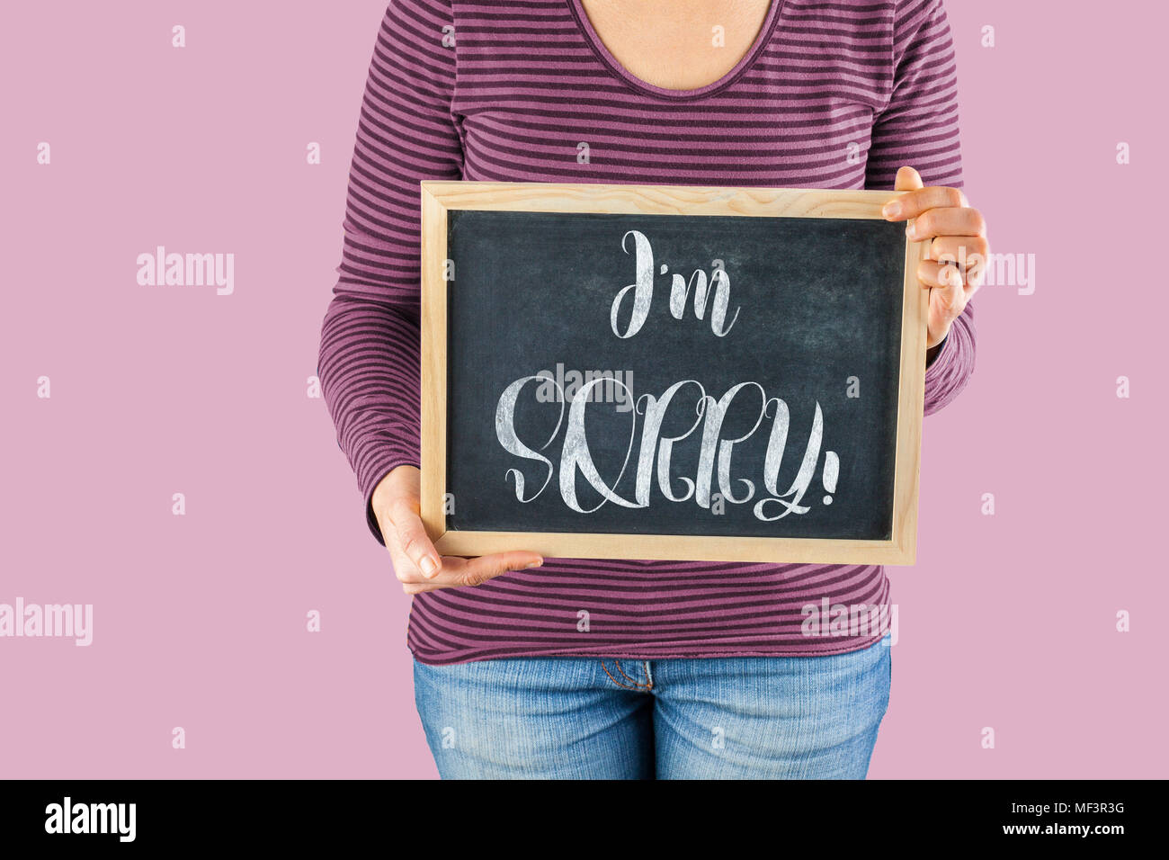 Female hands holding small black chalkboard in front of the body with written words saying I'm Sorry Stock Photo