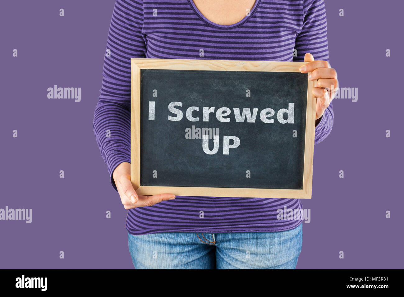 Female hands holding small black chalkboard in front of the body with written words saying I screwed up Stock Photo