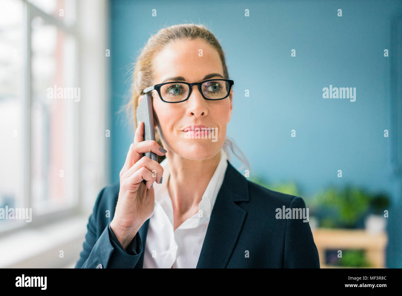 Successful businesswoman standing at home, talking on the phone Stock Photo