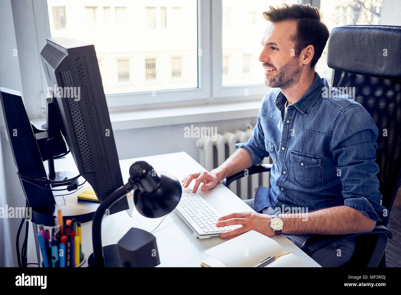 Smiling man working on computer at desk in office Stock Photo