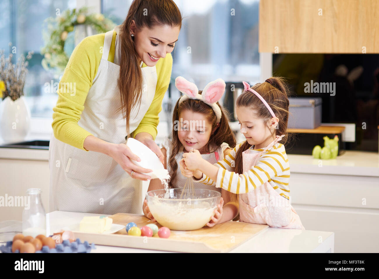 Mother and daughters baking Easter cookies in kitchen together Stock Photo