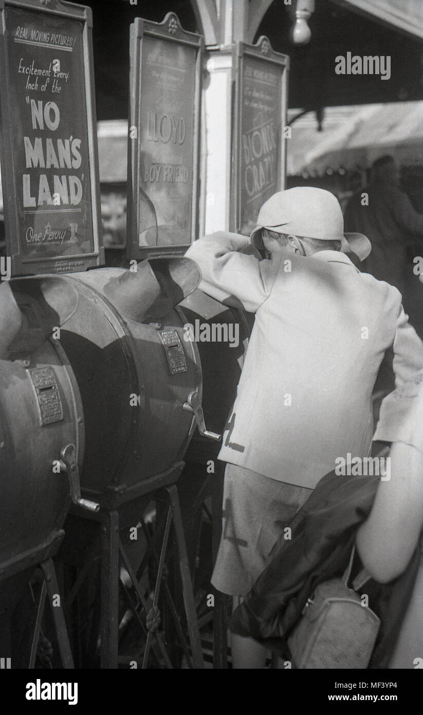 1940s, historical, young schoolboy using a mutoscope arcade movie viewer at a funfair, London, England, UK. These coin-operated machines contained a reel of still card pictures that fliped thereby giving an animated movie or film. Stock Photo