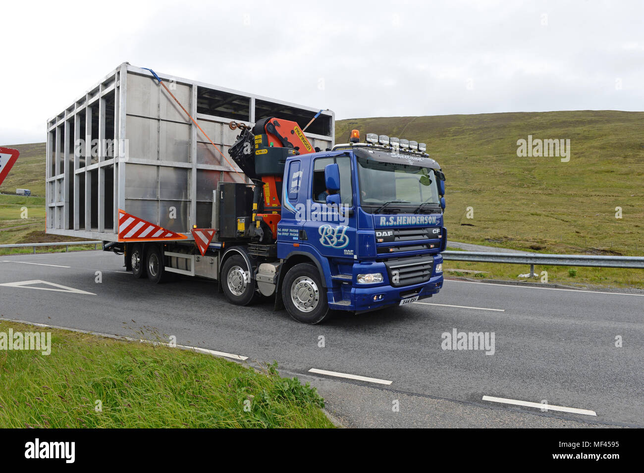 Wide load being moved by a truck through narrow roads Stock Photo