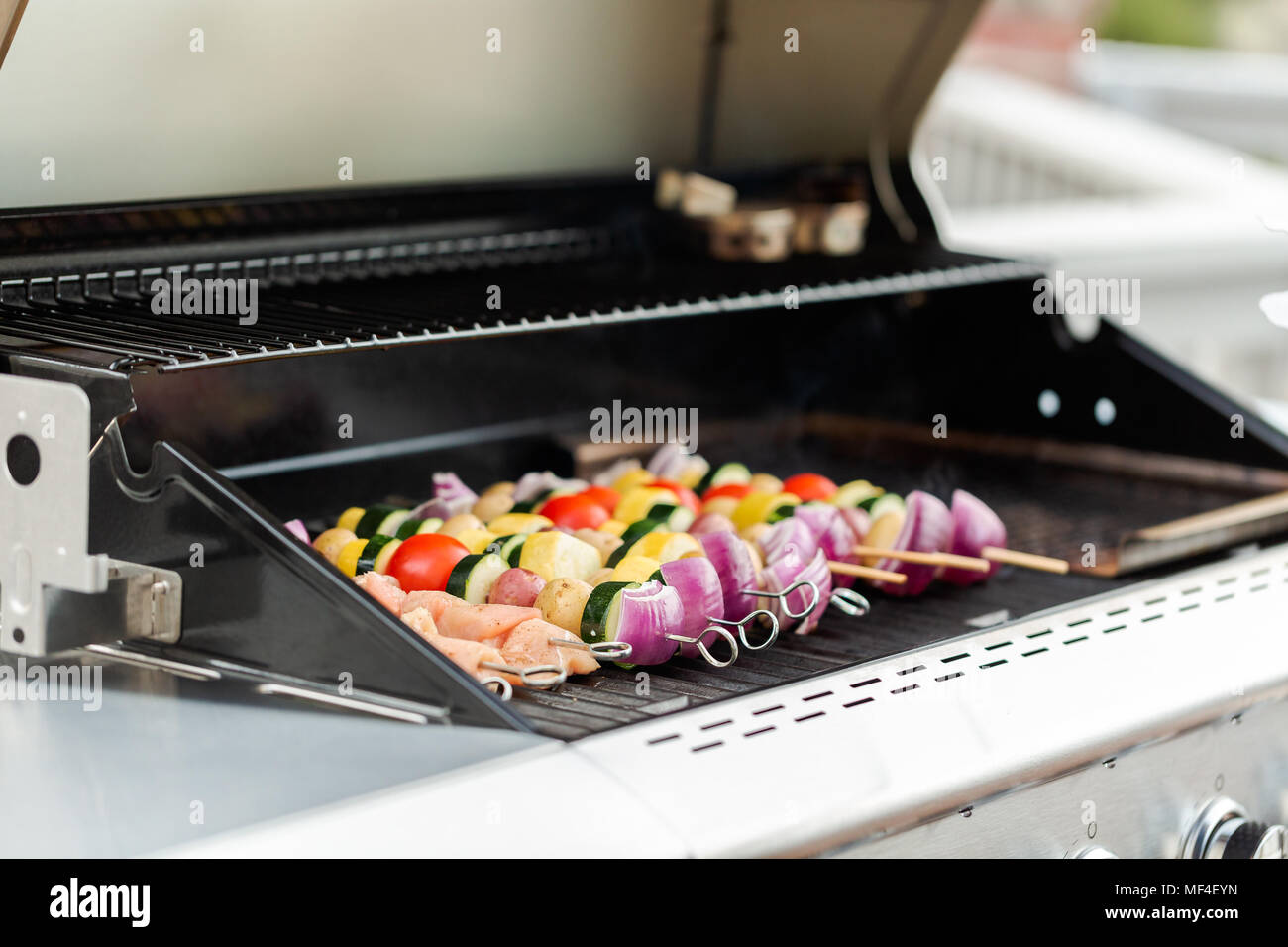 Step by step. Grilling veggie skewers and chicken kebabs on outdoor gas