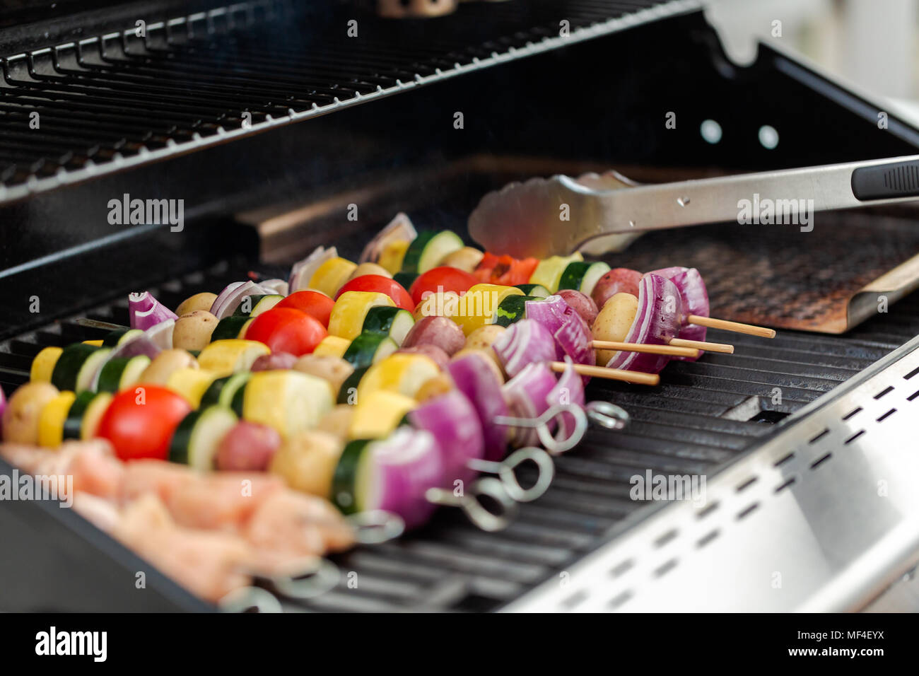 Step by step. Grilling veggie skewers and chicken kebabs on outdoor gas