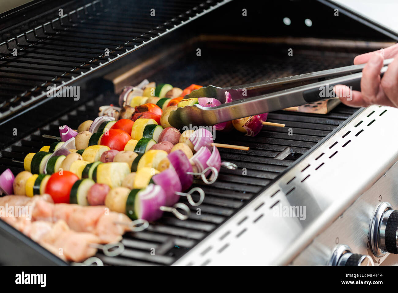 Step by step. Grilling veggie skewers and chicken kebabs on outdoor gas