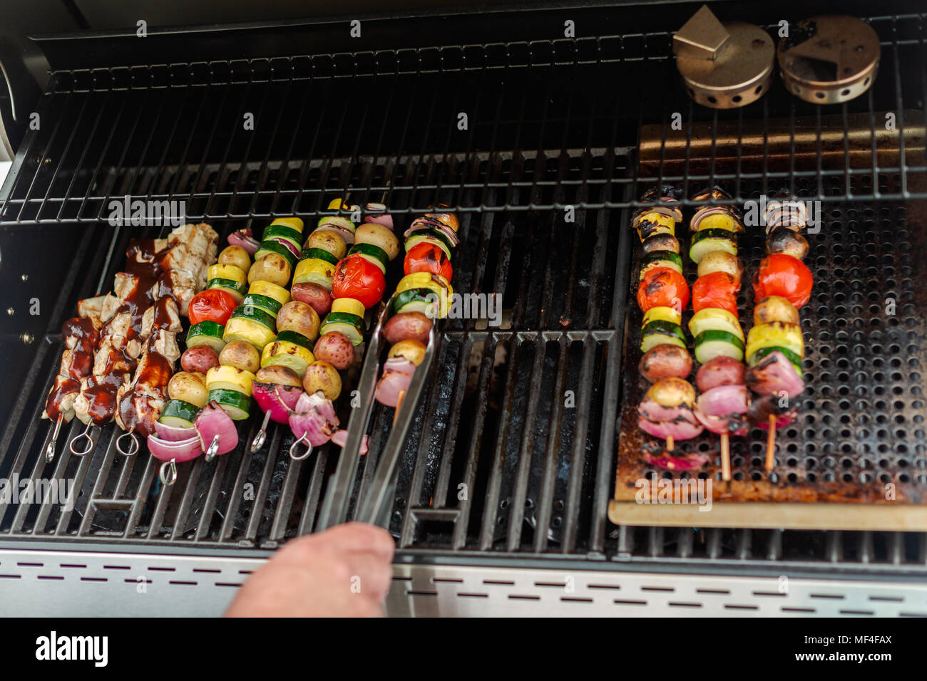 Step by step. Grilling veggie skewers and chicken kebabs on outdoor gas