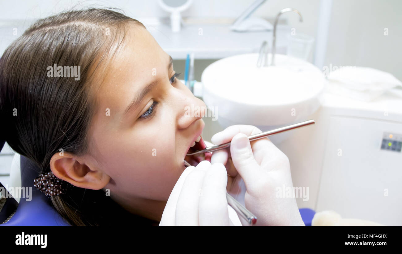 Closeup image of dentist hands in gloves examining girls teeth with instruments Stock Photo